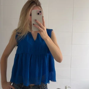 Blå söt blus från Cache Cache - Säljer en så söt och snygg blå ärmlös blus från Cache Cache. Blusen har en luftig design med volanger och är perfekt nu till våren och sommaren. Använd fåtal gånger och jättebra skick!