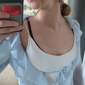 Ljusblå blus från H&M Divided - Säljer en ljusblå blus från H&M Divided. Blusen har långa ärmar och knytning framtill. Perfekt för en stilren look.