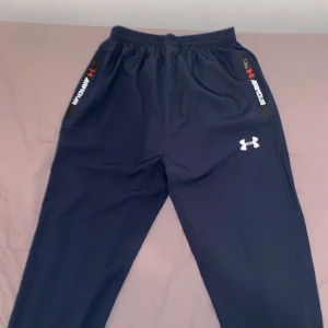  träningsbyxor Under Armour - Säljer ett par mörkblå träningsbyxor från Under Armour. Den är helt ny och i väldigt bra kvalitet.