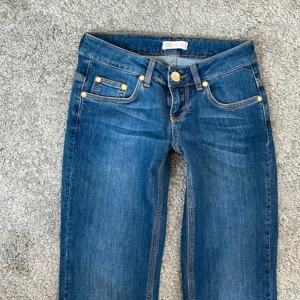 Lågmidjade bootcut jeans - Snygga blå lågmidjade bootcut jeans med klassisk femficksdesign och guldfärgade nitar. Perfekta för en avslappnad stil. De har en knapp och dragkedja framtill. Pris kan diskuteras!💕