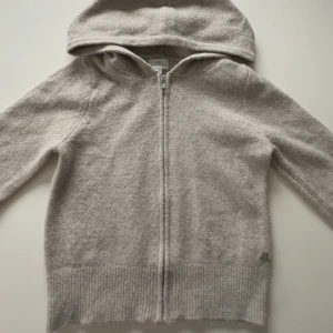 Beige hoodie från Pacific Republic - Mysig beige hoodie från Pacific Republic med dragkedja framtill. Tröjan har långa ärmar och en bekväm huva, perfekt för kyliga dagar. Ribbstickade muddar vid ärmslut och nederkant ger en skön passform. Tröjan är aldrig använd