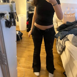 Svarta kostymbyxor - Snygga svarta kostymbyxor med en klassisk straight passform. De har en midwaist design och är perfekta för en stilren look. Byxorna har diskreta fickor och en dragkedja framtill.