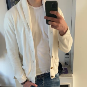 Vit kofta från Morris - Säljer en stilren vit kofta från Morris i storlek S. Koftan är tillverkad i 100% bomull och har knappar framtill samt ribbade muddar. Perfekt för en avslappnad och snygg look. Denna säljs inte längre därav priset. Ny pris ligger på 1699kr