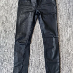 Svarta skinny jeans från Burberry - Snygga svarta skinny jeans från Burberry i en blandning av bomull och polyester med en touch av elastan för extra stretch. De har en klassisk femficksdesign och en knappgylf. Perfekta för en stilren look.  Svarta jeans med skinnlook i strl W27 från Burberry, modell skinny low rise.  Använda men i fint begagnat skick.  Mått Midjan: ca 40 cm Längd från grenen och ner: ca 74 cm  89% bomull, 7% polyester och 4% elastan  Kommer från ett djur och rökfritt hem. 