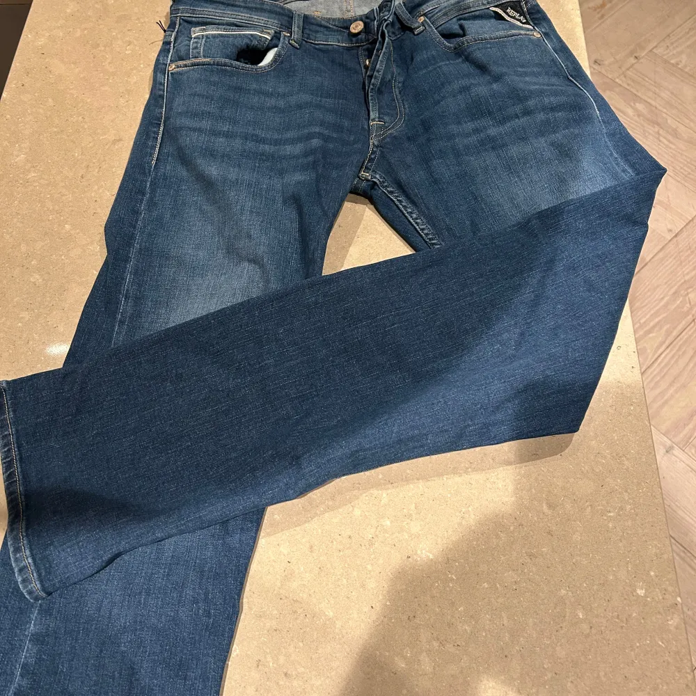 Snygga blå jeans från Replay, modell Grover med straight fit. Tillverkade i hållbart material med klassisk femficksdesign och knappgylf. Perfekta för en stilren look. Helt oanvända och sprillans nya.. Farkut & Housut.