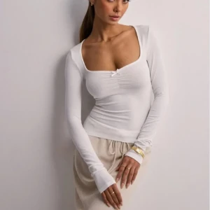 Vit långärmad topp - Snygg vit långärmad topp med en djup fyrkantig urringning och åtsittande passform. Perfekt för en stilren look. Aldrig använd med prislapp kvar💓 