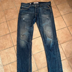 Blå replay jeans med slitningar  - Snygga blå jeans från Replay med slitna detaljer. Storleken är W33 L32. Använda under fåtal tillfällen, eftersom modellen inte passar så bra för mig. Priset jag säljer för är 950kr, köpta för 1799kr