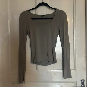 Grön långärmad topp - Säljer en stilren grön långärmad topp med rund halsringning. Toppen har en slitsdetalj vid ärmsluten.