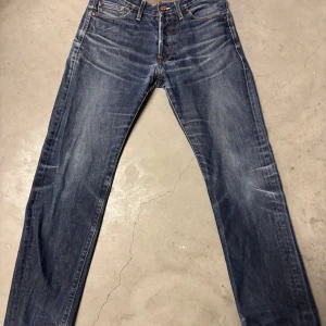 Blå jeans från Acne - Snygga blå jeans från Acne med klassisk femficksdesign och knappgylf. Jeansen har en rak passform och är perfekta för en avslappnad stil. Märkeslappen i läder sitter på baksidan av midjan.  Storlek 29/34 men passar mindre på längden 