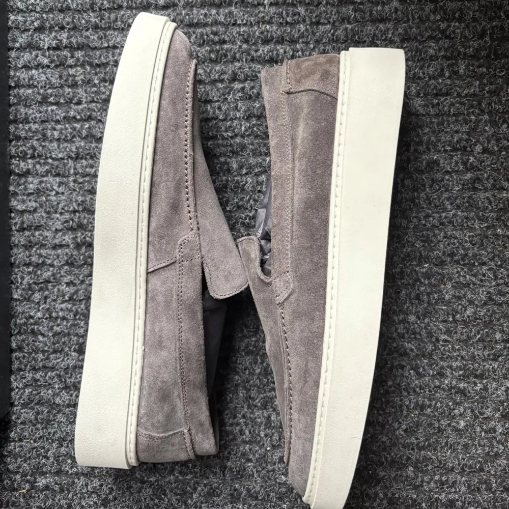 Snygga gråa loafers i mocka från Massimo Dutti. Skorna har en stilren design med en vit sula som ger en modern touch. Perfekta för en avslappnad men ändå elegant look. Aldrig använda endast testade, köpta i Göteborg och var för stora. Kengät.
