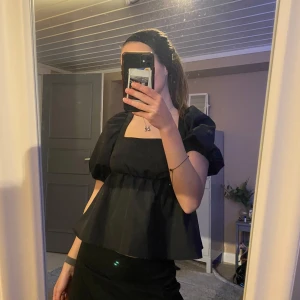 Svart blus med öppen rygg och knytband - Säljer en elegant svart blus med puffiga korta ärmar och en vacker öppen rygg med knytband. Perfekt för en stilren look. Använd 1 gång🫶🏼