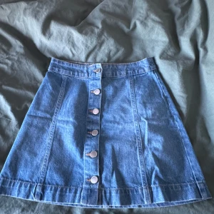 Jeanskjol - Blå jeanskjol med silvriga knappar fram. Perfekt nu till sommaren