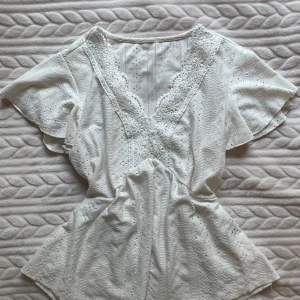 Vit blus  - Säljer en söt vit blus från Shein med v-ringning och spetsdetaljer ⚡️Blusen har korta ärmar och ett luftigt fall, perfekt för varma dagar. Den är tillverkad i ett lätt och bekvämt material 💞 