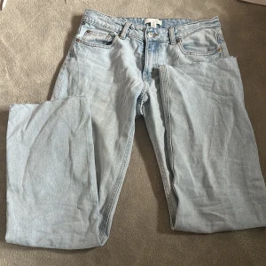 Ljusblå jeansbyxor - Säljer ett par ljusblå jeansbyxor med klassisk femficksdesign. Byxorna har en normal passform och är tillverkade i denim. Perfekta för en avslappnad stil. Raka midjemått: 39cm innerbensmått: 77cm. Det är ett hål på knät, därav priset!