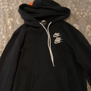 Svart hoodie från Nike - Säljer en svart hoodie från Nike med vit logga på bröstet och texten 'MOVE YOUR BODY' i stora bokstäver längs ärmen. Hoodien har en klassisk design med dragsko i huvan och en stor magficka. Perfekt för en sportig look! Den lyser även i mörker. Neon färger väldigt snyggt när det är mörkt.
