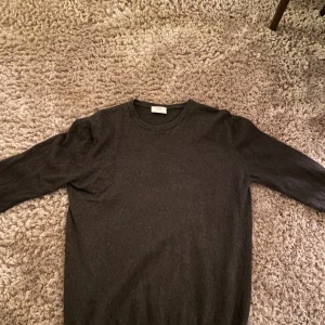 Mörkgrå tröja från Filippo Riberti - Säljer en stilren mörkgrå tröja.Tröjan är långärmad och har en klassisk rund halsringning. Perfekt för kyligare dagar och enkel att matcha med olika outfits. Helt nytt skick och fin stickad 