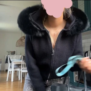 Alessa jacka (!INTRESSEKOLL!) - Snygg svart stickad jacka med dragkedja och huva kantad med fuskpäls. Perfekt för kyliga dagar med sin mysiga och stilrena design. Jackan har långa ärmar och ribbade muddar för extra komfort. Första 3 bilderna är mina egna och de två sista är från alessas medier🩷🩷 de är one size men skulle säga att det är storlek S. Jag har använt den i typ 1 månad nu. Köpte den för 1600kr