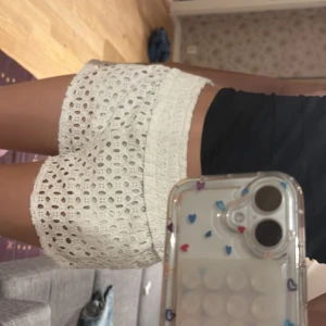 Vita spets shorts - Säljer ett par vita shorts med vacker spetsdesign. De har en lös passform och är perfekta för sommardagar. Shortsen har en elastisk midja för extra komfort. Det är M men skulle säga att det också passar xs dem har jätte fint skick 💗💗