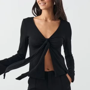 Svart långärmad topp från Gina Tricot - Snygg svart långärmad topp från Gina Tricot med knytning framtill. Toppen har en v-ringad design och är tillverkad i ett mjukt material.