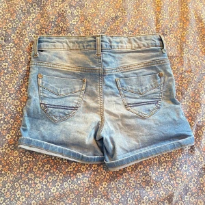 Blå jeansshorts - Säljer ett par snygga blå jeansshorts. De har en klassisk femficksdesign med knapp och dragkedja framtill. Perfekta för sommardagar! De var uppvikta förut men har sprättat upp d så man kan lätt klippa av om man vill ha kortare🥰🥰sitter som xxs