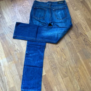 Blå jeansbyxor från Acne jeans - Säljer ett par klassiska blå jeansbyxor från acne jeans med en straight passform. Byxorna har en lätt slitning på framsidan. Perfekta för en laidback stil.
