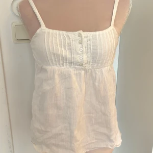 Vit babydoll linnetopp  - Säljer en söt vit linnetopp från H&M Young med smala axelband och knappar framtill. Toppen har en lätt rynkad design och är perfekt för varma dagar♥️♥️. 🌸 passar stl XXS!