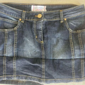 Jeanskjol från Coconda Fashion - Snygg jeanskjol från Coconda Fashion i en klassisk blå denim. Kjolen har dekorativa sömmar och två bakfickor med söta rosetter.  Midjemått: 42cm längdmått: 31cm 💛💛💛