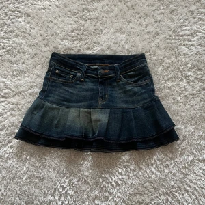 Jeanskjol med volang - En lågmidjad jeanskjol omsydd från ett par jeans Midjemått tvärsöver - 36 cm Längd - 33cm