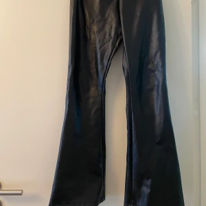 Svarta skinnbyxor från Dry Lake - Snygga svarta skinnbyxor från Dry Lake med en cool bootcut-stil. Perfekta för att ge din outfit en edgy touch. Byxorna har en glansig finish som verkligen sticker ut.