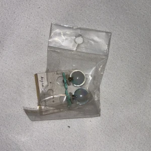 Blå och gröna örhängen med blomdetalj - Snygga örhängen med en rund blå sten och gröna blomdetaljer. Perfekta för att ge en färgklick till din outfit.