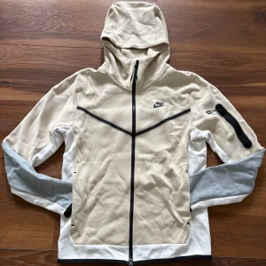 Nike Tech Set - Säljer mitt beiga Nike Tech set som endast är använd ett fåtal gånger. Den är i mycket fint skick, inga fläckar eller skador. Snygg passform, bekväm och perfekt för både vardag och träning. Köpt på JD för ca 3000 kr – mitt pris: 1500 kr.