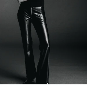 Svarta skinnbyxor med dragkedja - Snygga svarta skinnbyxor med en tight passform och dragkedja framtill. Byxorna har en modern bootcut-stil som ger en trendig look. Perfekta för att ge din outfit en edgy touch. Storlek 34