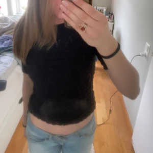 Svart ribbad topp från Lindex - Säljer en svart ribbad topp från Lindex i storlek XS. Toppen har en croppad passform och korta ärmar, perfekt för en stilren look. Tillverkad i ett bekvämt material som ger en snygg struktur.