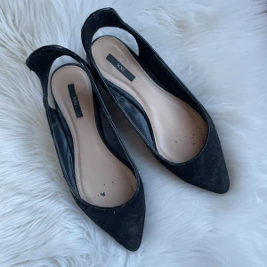 Svarta kitten heels med spetsig tå - Svarta kittenheels. Från början hade de ett spänne som satt runt vristen, detta är nu borttaget men därav hälkappan. Inget man tänker tillsammans med byxor🫶🏼