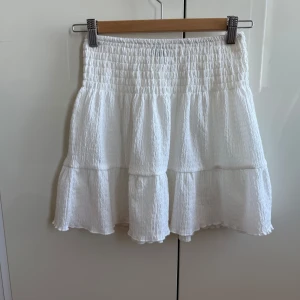 Vit kjol från Gina Tricot - Kjolen har en smockad midja och volangdetaljer!! Perfekt till varma sommar dagar 💕☀️