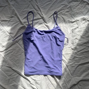 Lila linnetopp med smala axelband - Snygg lila linnetopp med smala axelband. Perfekt för varma sommardagar eller som ett lager under en tröja. Enkel och stilren design som passar till det mesta.