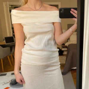 Vit offshoulder topp - Säljer en stilren vit offshoulder topp. Perfekt för en elegant look med sin axelbandslösa design. Toppen har en tight passform som framhäver figuren. Jag själv är storlek S så passar bra 
