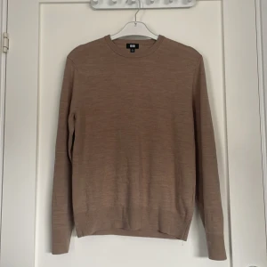 Beige/brun merinulls tröja från Uniqlo - Säljer en stilren beige merinoulls tröja från Uniqlo i storlek xs men sitter lite tajtare än xs. Tröjan är långärmad och har en klassisk rund halsringning. Tröja är ny utan prislapp alltså inte använd någon gång. 