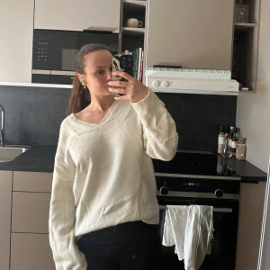 Vit stickad tröja med v-ringning - Säljer en mysig vit stickad tröja med v-ringning. Tröjan har långa ärmar och en avslappnad passform, perfekt för kyligare dagar. Passar bra till både jeans och kjol. Hör av dig vid intresse!