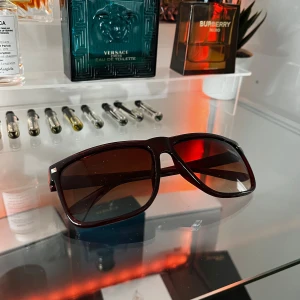 Solglasögon - Snygga bruna solglasögon med fyrkantig form och mörka linser. Perfekta för en stilren look. Ramen har en glansig finish och små silverdetaljer vid gångjärnen.