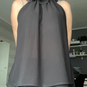 Svart halterneck blus med volang - Säljer en svart halterneck blus med snygga volangdetaljer vid halsen.