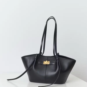 Svart axelväska med gulddetalj - Stilren svart axelväska i skinn med långa smala axelband och snygg guldfärgad vridknäppning framtill. Väskan har en modern, något utsvängd form och minimalistisk design som passar perfekt till en trendig look. (Midi long strap bag - Gina tricot). Ord. pris 399kr. Lånad bild.