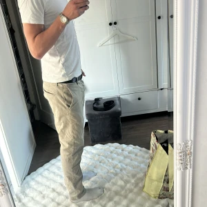 Beige vintage Replay Hyperflex chinos - Säljer ett par snygga beige chinos från Replay Hyperflex. Byxorna har klassisk passform med dragkedja, bälteshällor och bakficka med dragkedja. Sköna och stretchiga i bomullsmix, perfekta för en clean och avslappnad look. 