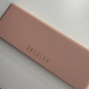 SHEGLAM ögonskuggspalett rosa/neutral - Snygg ögonskuggspalett från SHEGLAM med 12 nyanser i rosa, nude, brunt och lila. Kommer i en stilren rosa förpackning med spegel + en sminkborste. Knappt använd. Nån enstaka färg som är använd nån gång. 