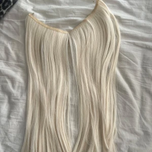 Blonda löshår tråd - Långa, raka löshår i tråd i en superljus blond nyans. Perfekt för att få extra längd och volym till håret. Fästet syns inte och smidigt att använda för en naturlig look.