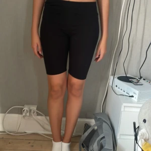 Svarta cykelshorts från H&M - Svarta cykelshorts från H&M i stretchigt material. De är midwaist och har en tight passform som sitter snyggt på kroppen. Perfekta för träning eller chill dagar. Klassisk och enkel design utan detaljer eller mönster.