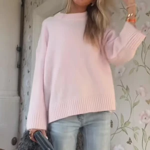 Ljusrosa stickad oversized tröja - Supermysig ljusrosa stickad tröja med oversized passform och breda, ribbade muddar vid ärmslut och nederkant. Tröjan har en enkel, rak modell och hög halsringning. Perfekt att slänga på sig för en chill och stilren look.