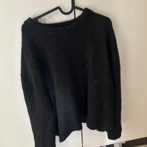 Svart stickad tröja från Gina Tricot - Mysig svart stickad tröja från Gina Tricot i storlek XS. Tröjan har en rund halsringning och långa ärmar, perfekt för lager på lager. Enkel och stilren design som funkar till många olika outfits.