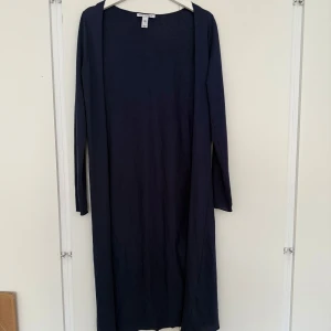 Mörkblå lång kofta från NLY Trend - Säljer en lång, mörkblå kofta från NLY Trend i storlek XS. Koftan har en enkel och stilren design utan knappar, med långa ärmar och ett mjukt material av polyester och bomull. Perfekt att slänga över en t-shirt eller topp för en chill look.