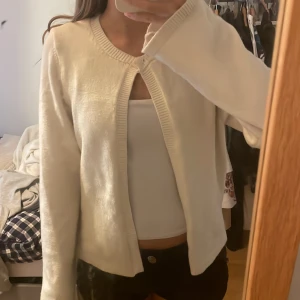 Vit kofta från Gina Tricot - Superfin vit kofta från Gina Tricot i storlek S. Den har långärmad design, rund halsringning och stängs med en liten knapp upptill. Koftan är stickad i mjukt material och har en clean, enkel look som passar perfekt till många outfits.